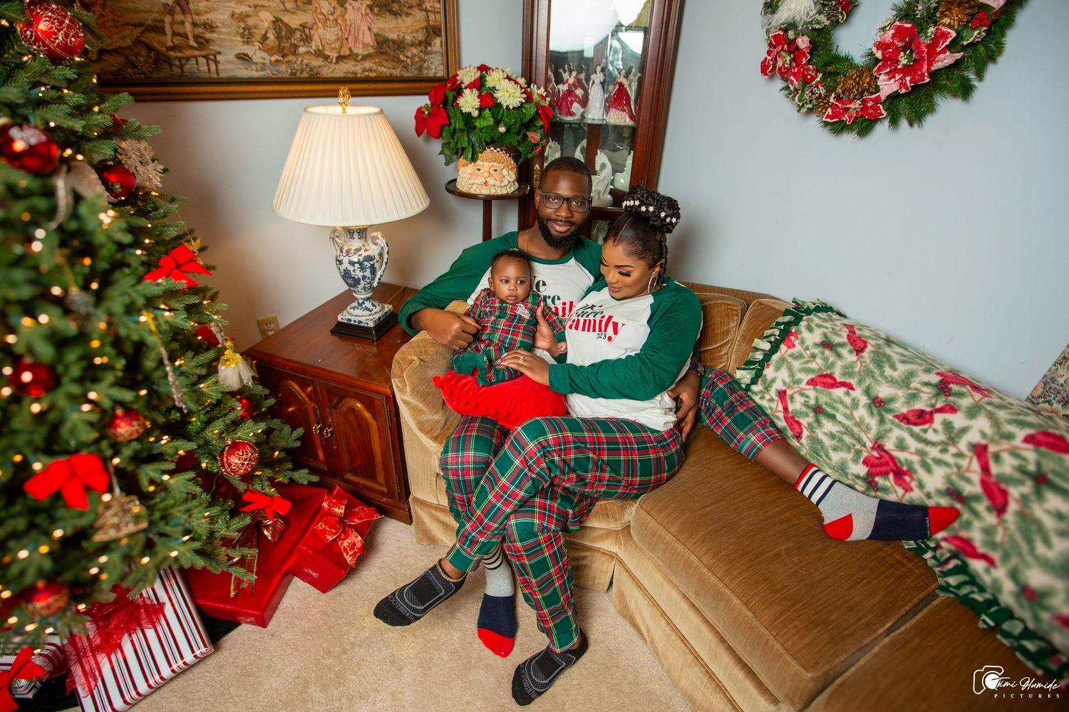 Cozy Christmas scene with children reading in armchair next to decorated tree and wrapped presents.