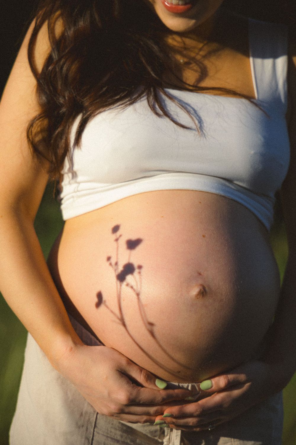 Pregnant belly close-up photo with the shadow of a flower on it during a vancouver outdoor maternity photo session.