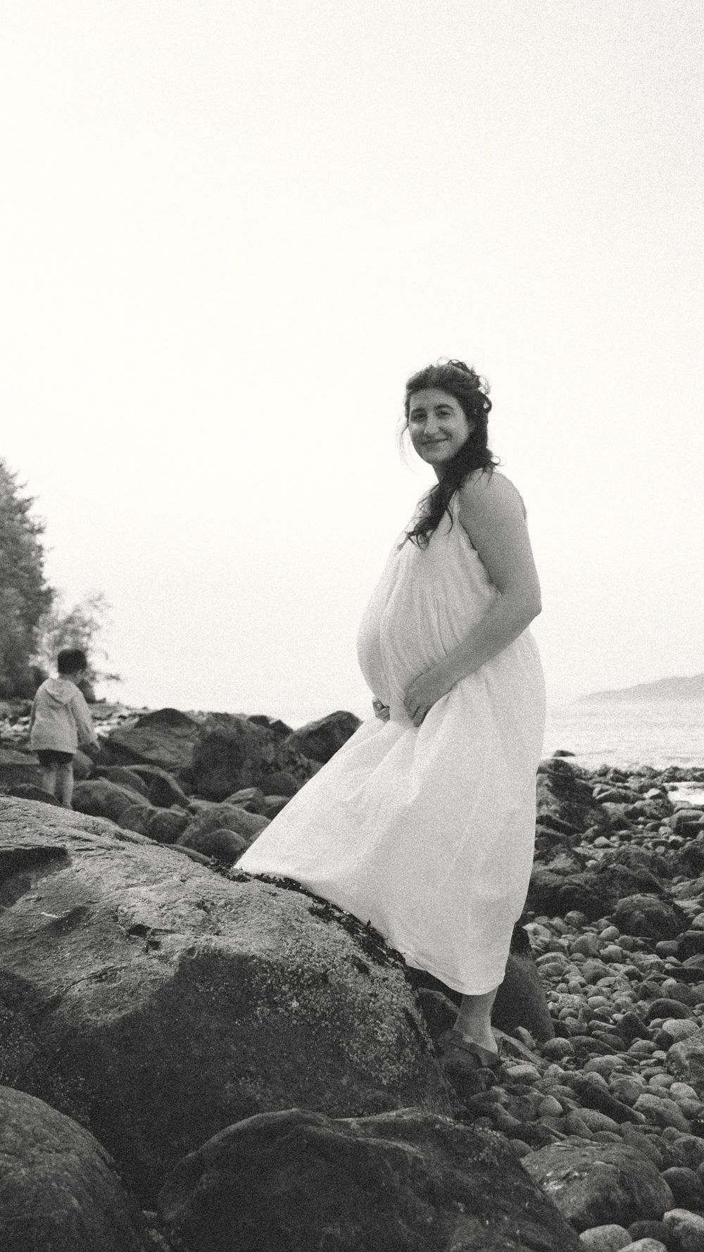 black and white photo of expecting mom in a flowy white dress during an outdoor beachy vancouver maternity session.