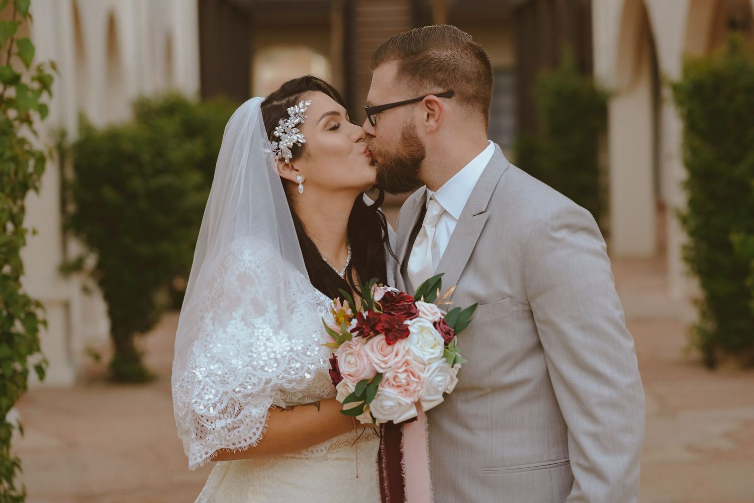A tender moment captured between a couple in wedding attire with pink floral bouquet.