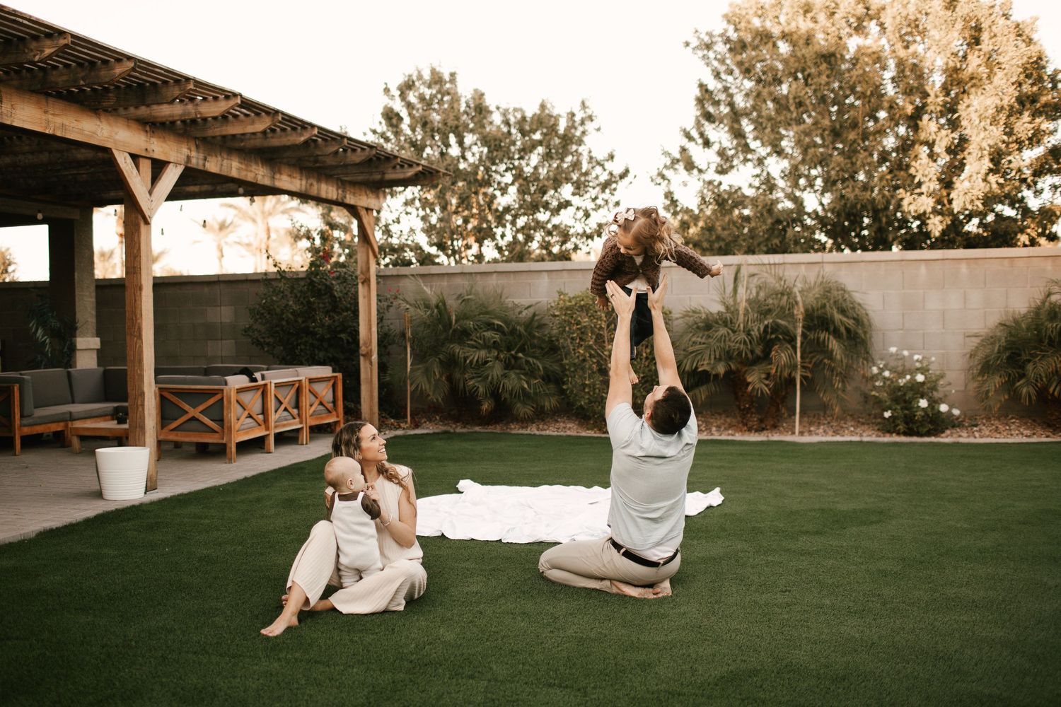 A sweet playtime moment in a backyard with a covered patio and artificial turf.