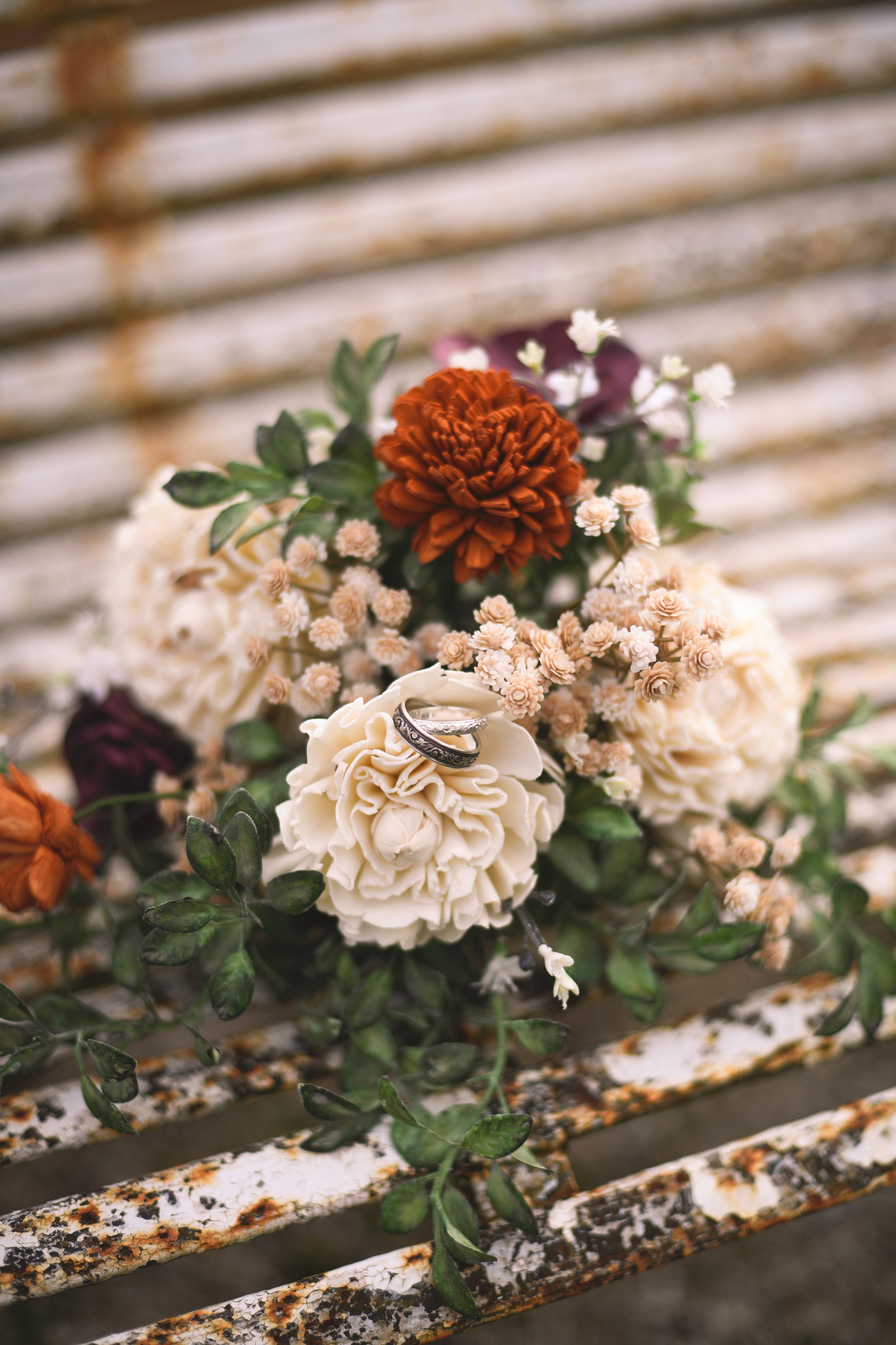 Detail shot of wedding rings and bouquet arranged with natural light and fine-art composition.