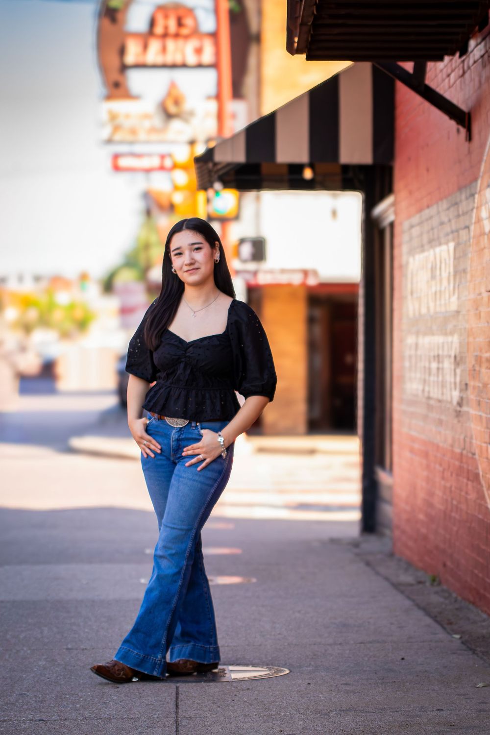 A series of outdoor photos showing someone posing in a black top and blue jeans against a brick wall backdrop.
