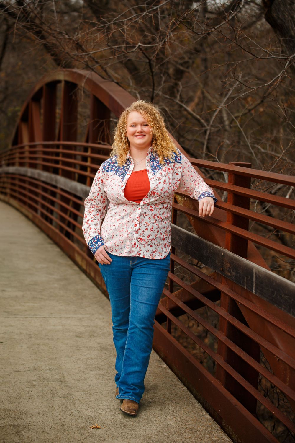 Portrait series on a wooden bridge walkway featuring someone in a floral top and jeans during autumn.