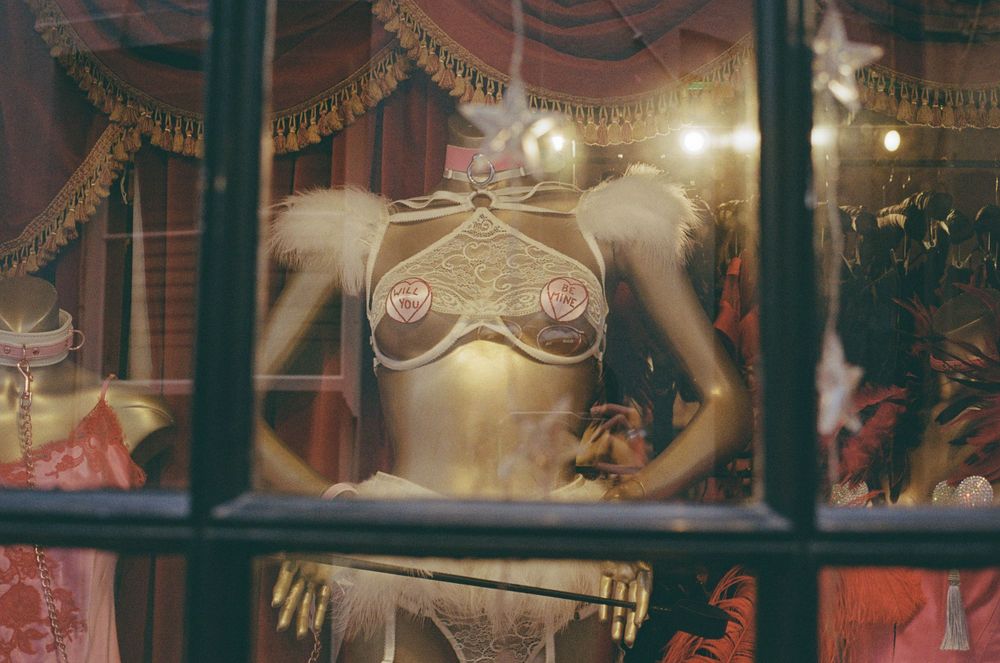 Vintage-style mannequin display in an illuminated shop window with draped decorations.