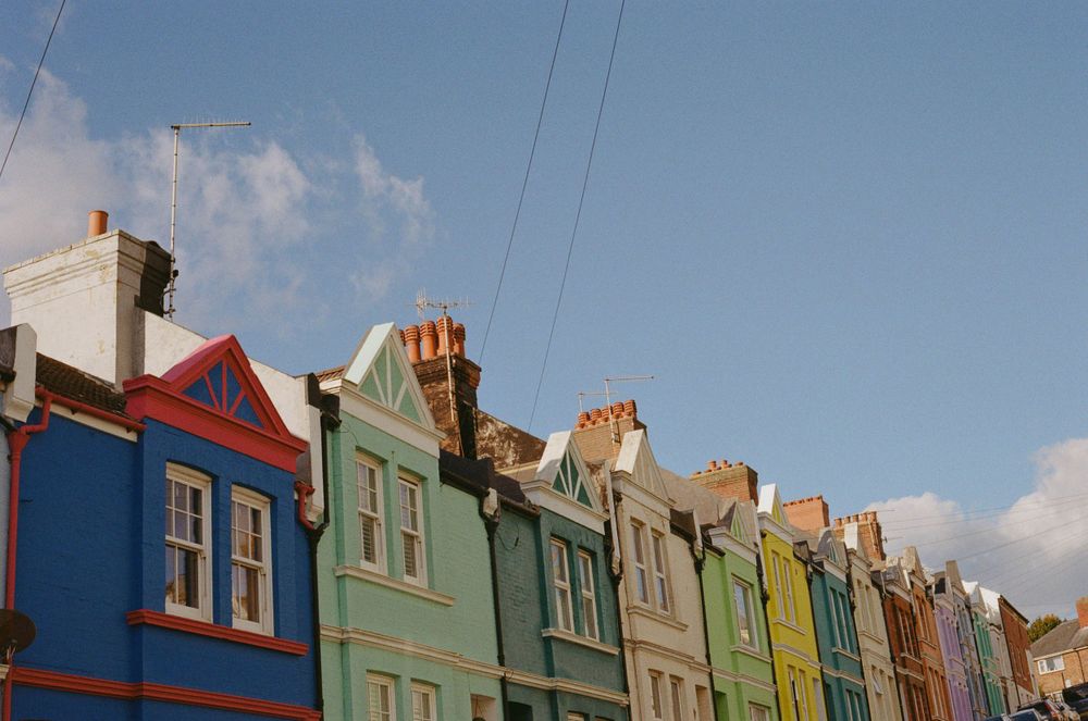 Colorful row of Victorian terraced houses with unique architectural details against blue sky.