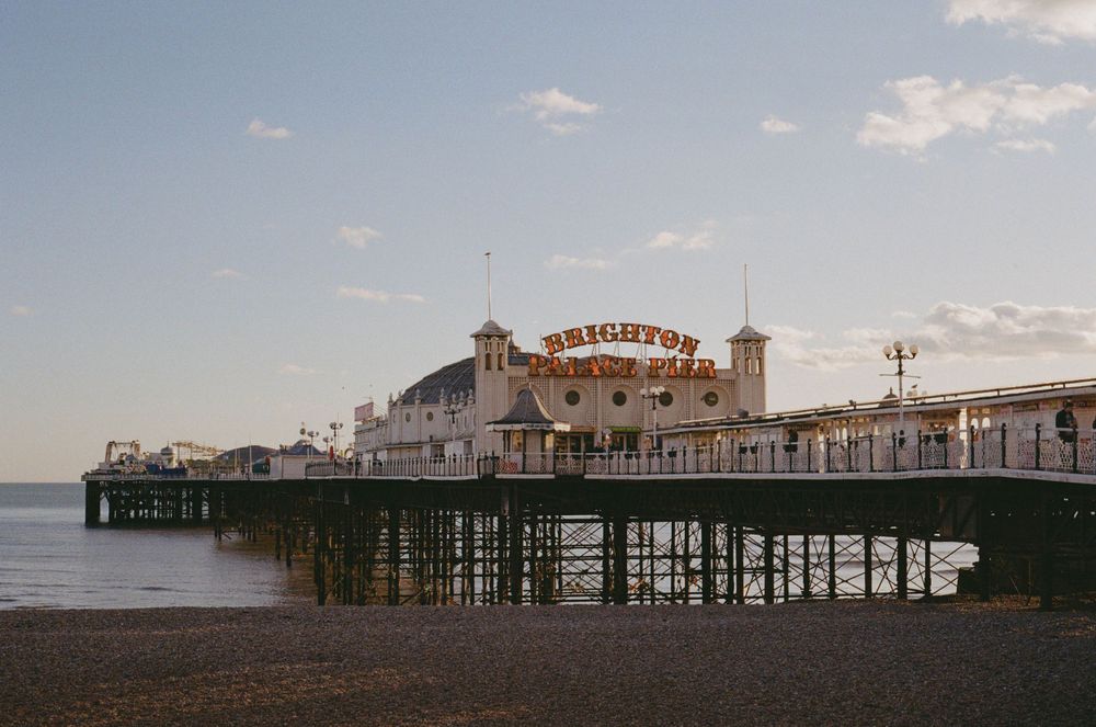 Brighton Pier stretching into the sea at dusk with its iconic architecture and amusement rides.