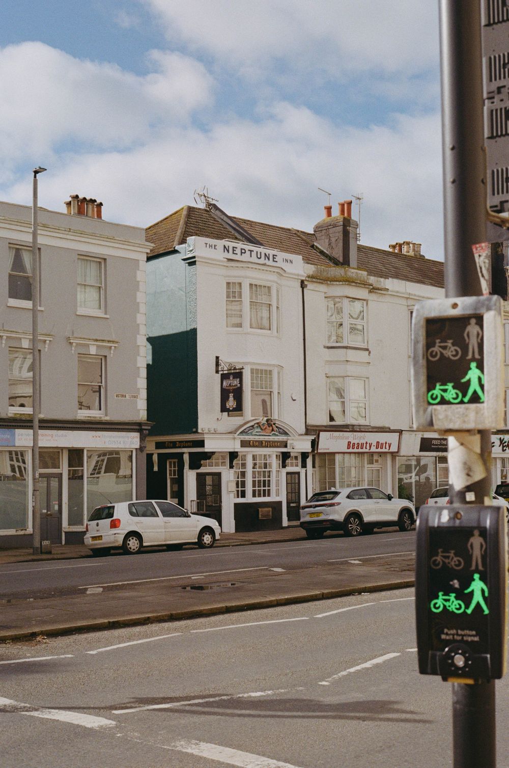 Classic British pub exterior with green and white facade and pedestrian crossing signals.