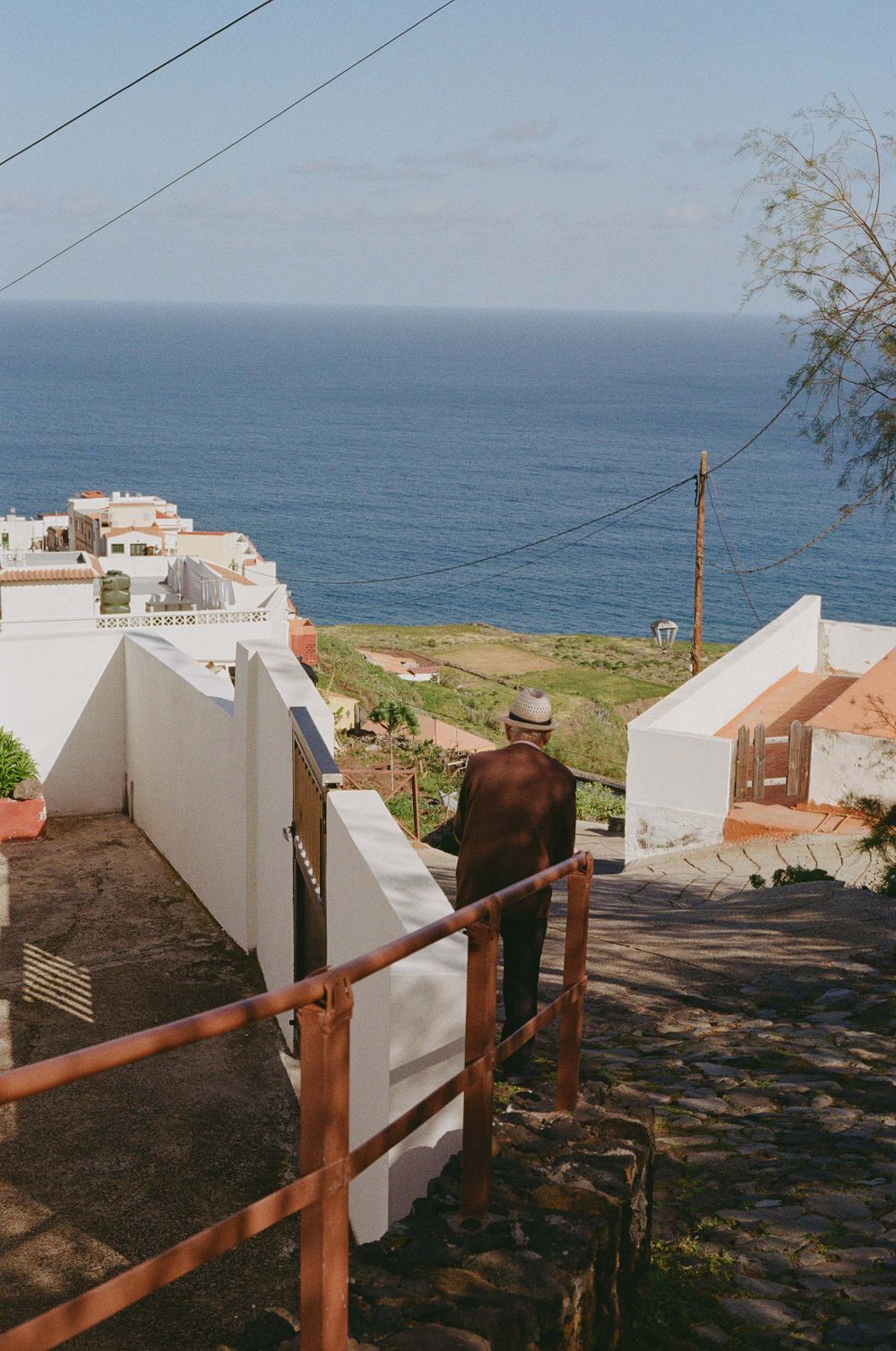 Coastal pathway with white buildings overlooking deep blue ocean waters.