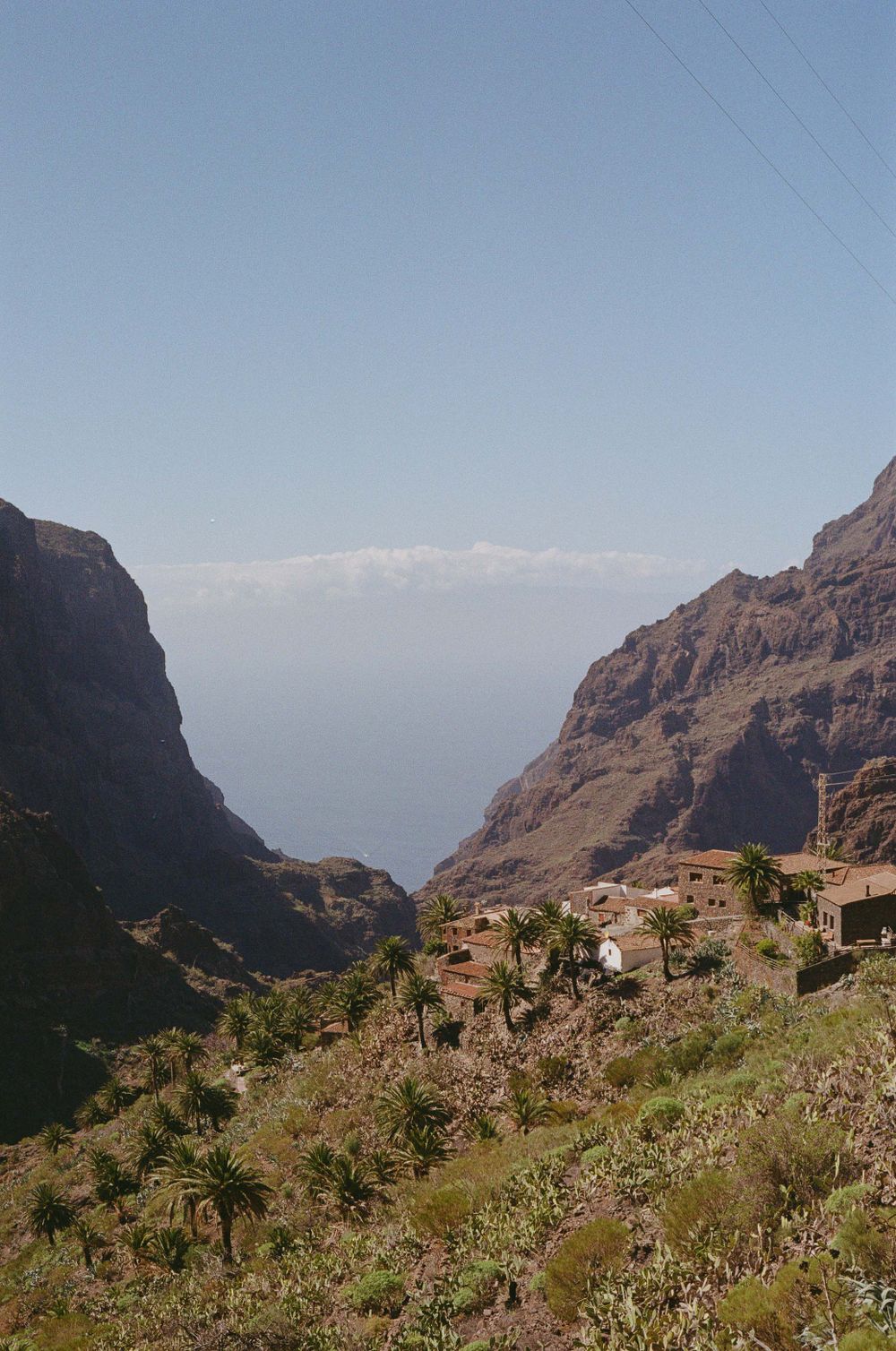 Dramatic mountain valley landscape with settlements nestled among rugged cliffs and lush vegetation.