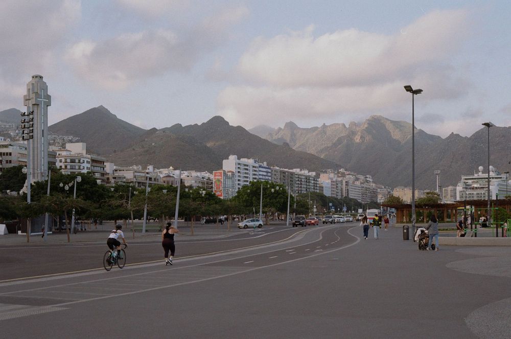Wide coastal road with mountains in background and cyclists.