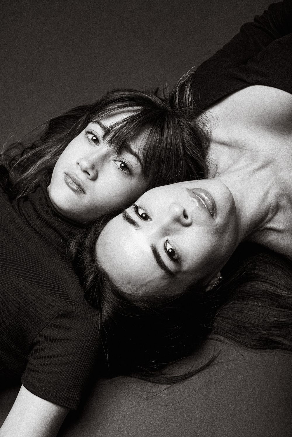 Artistic black and white portrait of two people laying head to head.