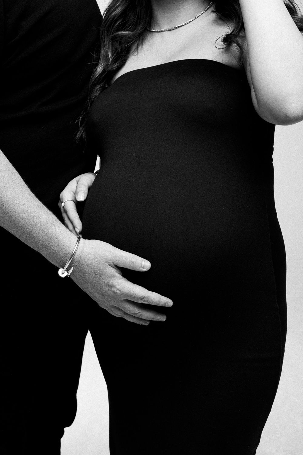 Black and white maternity photo showing hands cradling a pregnant belly.