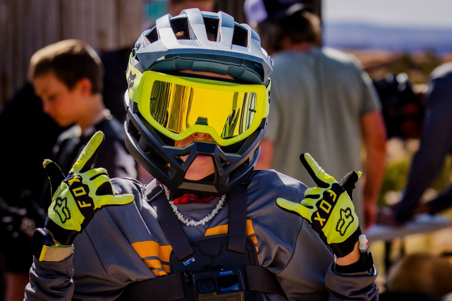 Mountain biker wearing protective gear with yellow goggles and helmet at outdoor event.