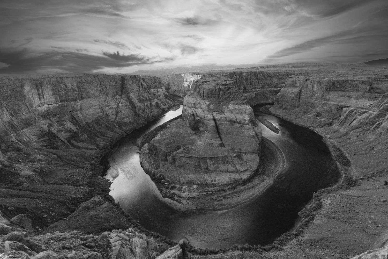 Dramatic aerial view of Horseshoe Bend on the Colorado River with sweeping canyon walls in black and white.