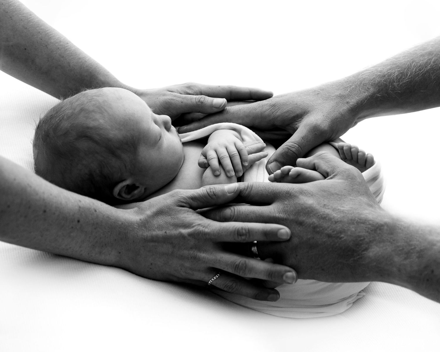 A peaceful newborn baby sleeps soundly while being cradled in a tender embrace.