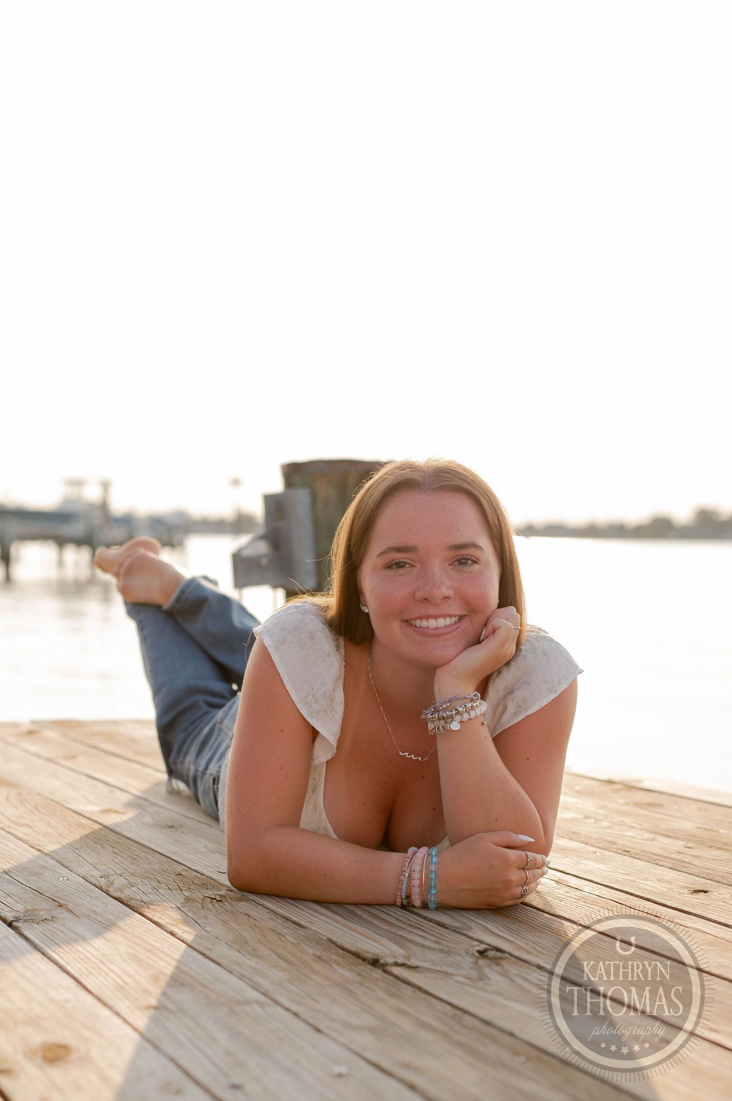 Person lying on wooden dock wearing casual attire during golden hour.