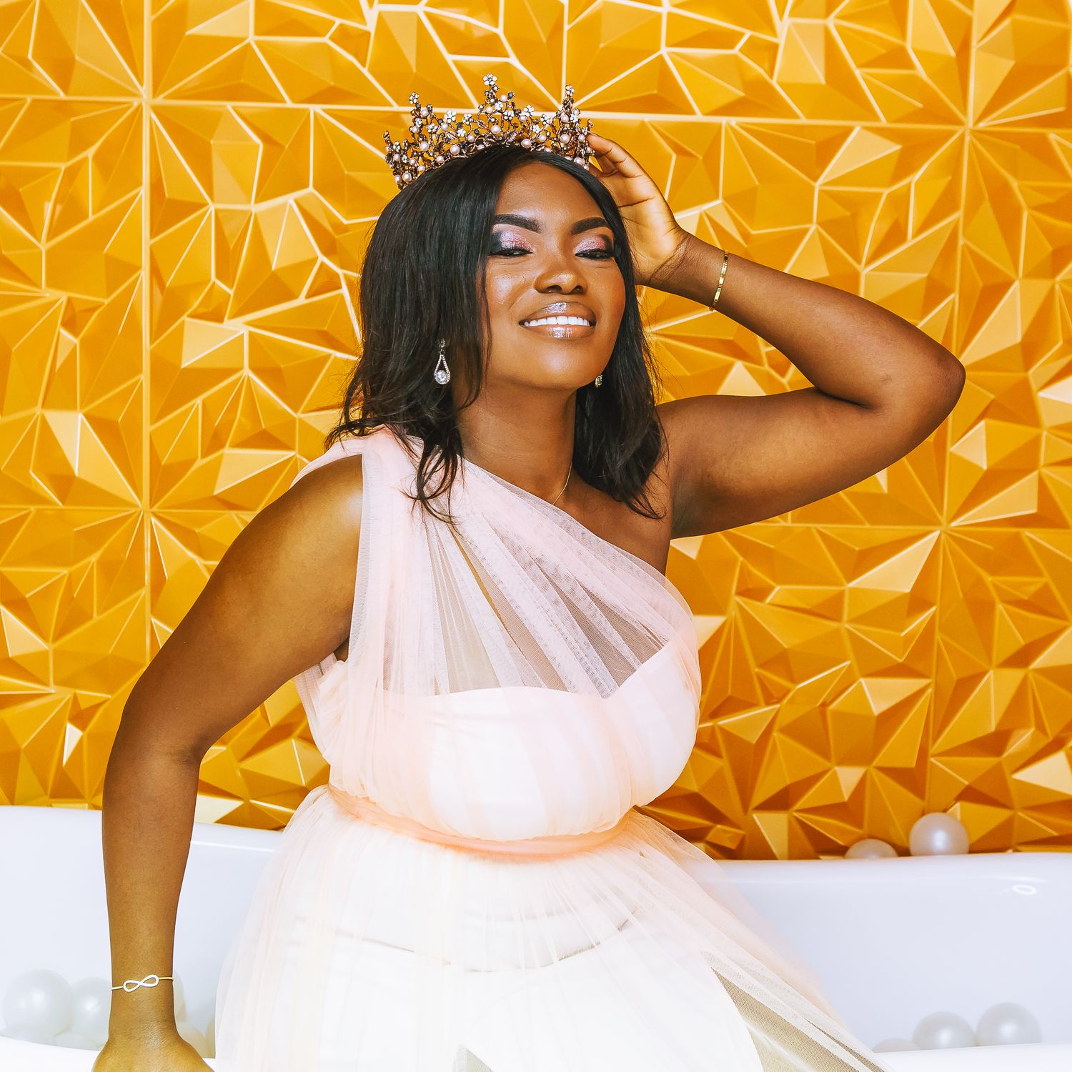 A graceful figure in a flowing white one-shoulder dress poses against a vibrant orange geometric backdrop with a crown.
