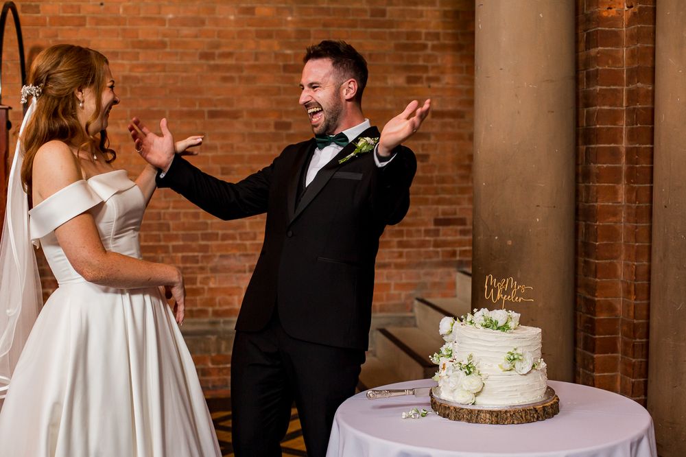 Couple laughs together during their wedding cake cutting ceremony.