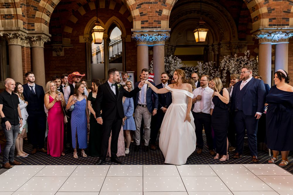 Wedding celebration in elegant venue with brick arches and illuminated dance floor.