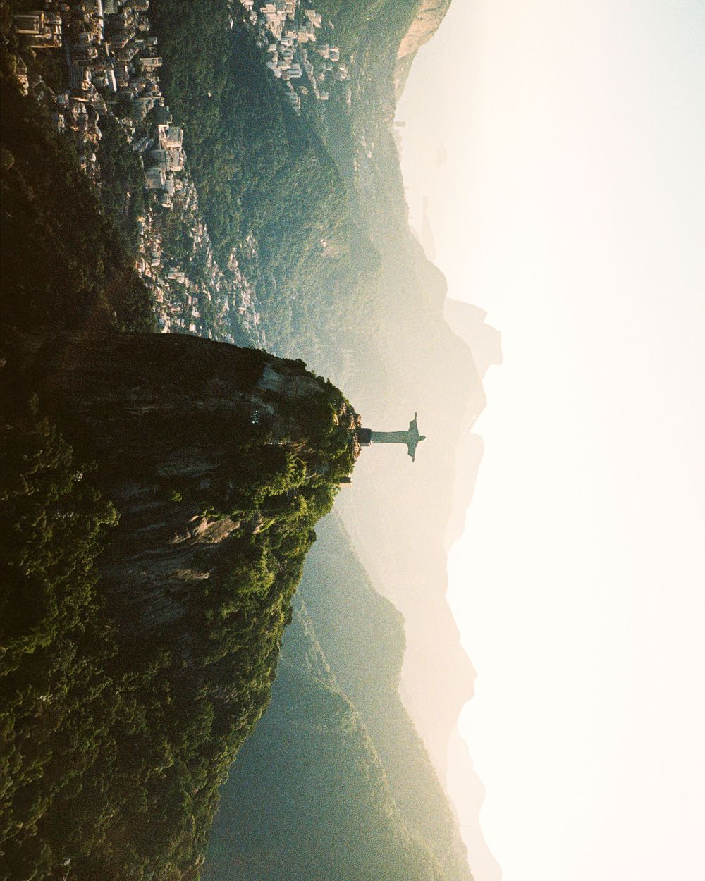Aerial view of Christ the Redeemer statue atop Corcovado mountain in Rio de Janeiro at golden hour.
