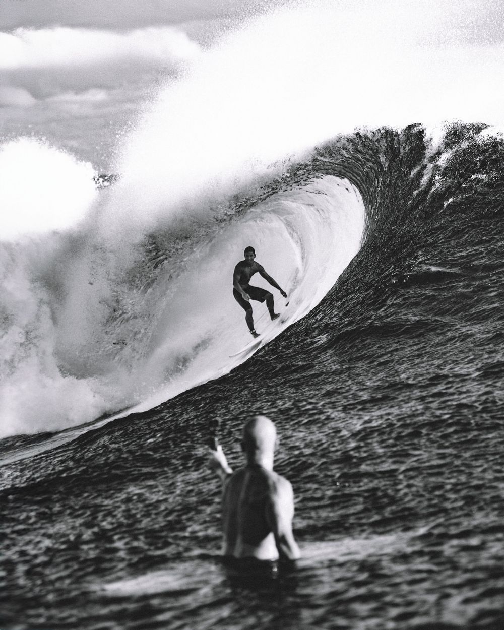 Black and white photo sequence showing a surfer riding and falling off a large breaking ocean wave.