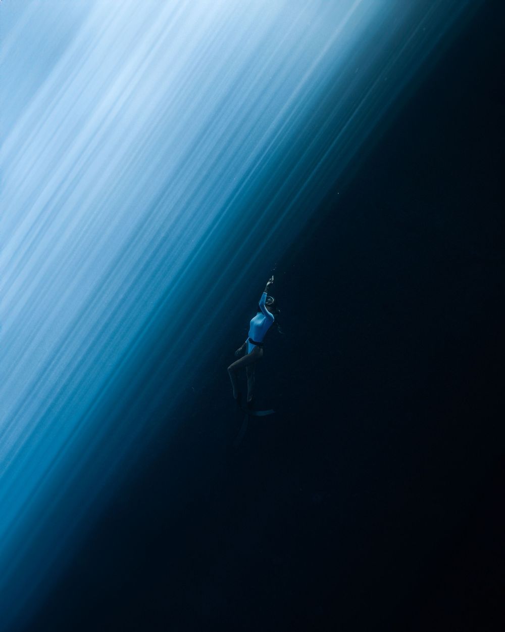 A silhouetted figure appears to be falling through a deep blue gradient background with streaks of light.