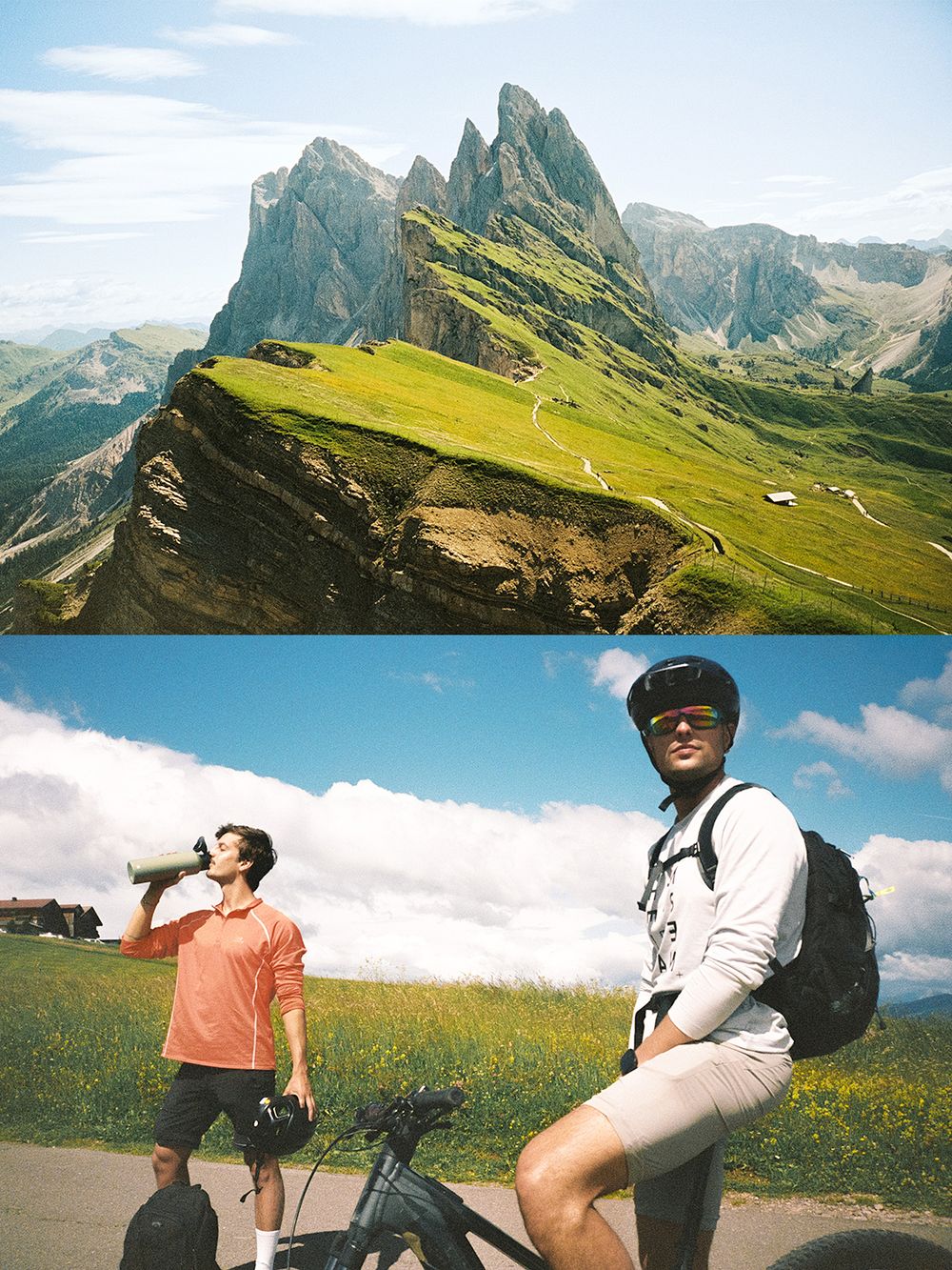 Two cyclists pause on a scenic mountain trail in the Dolomites, with dramatic rocky peaks and green meadows in the background.