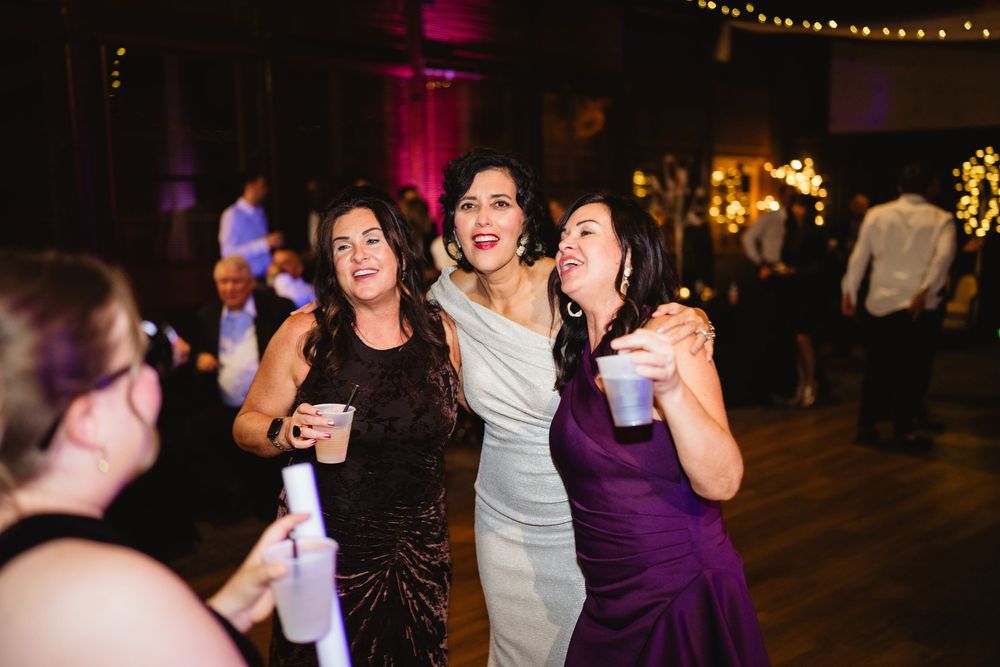 People dancing and celebrating at a dimly lit party venue with string lights creating a festive atmosphere.