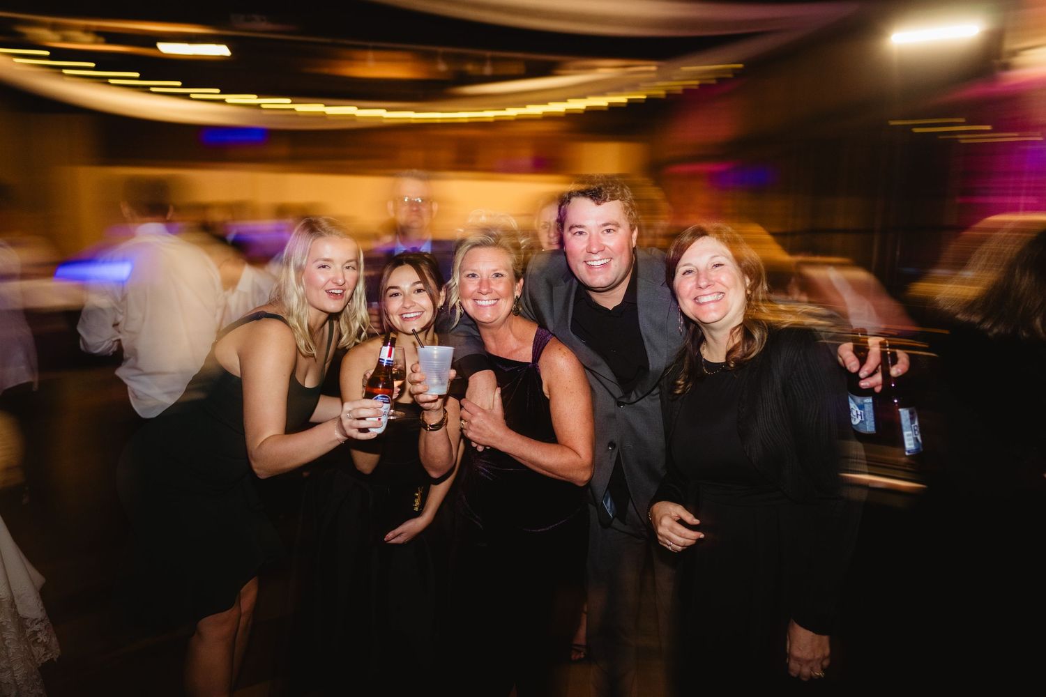 People enjoying a night out at a dimly lit bar or club with colorful lighting and festive atmosphere.