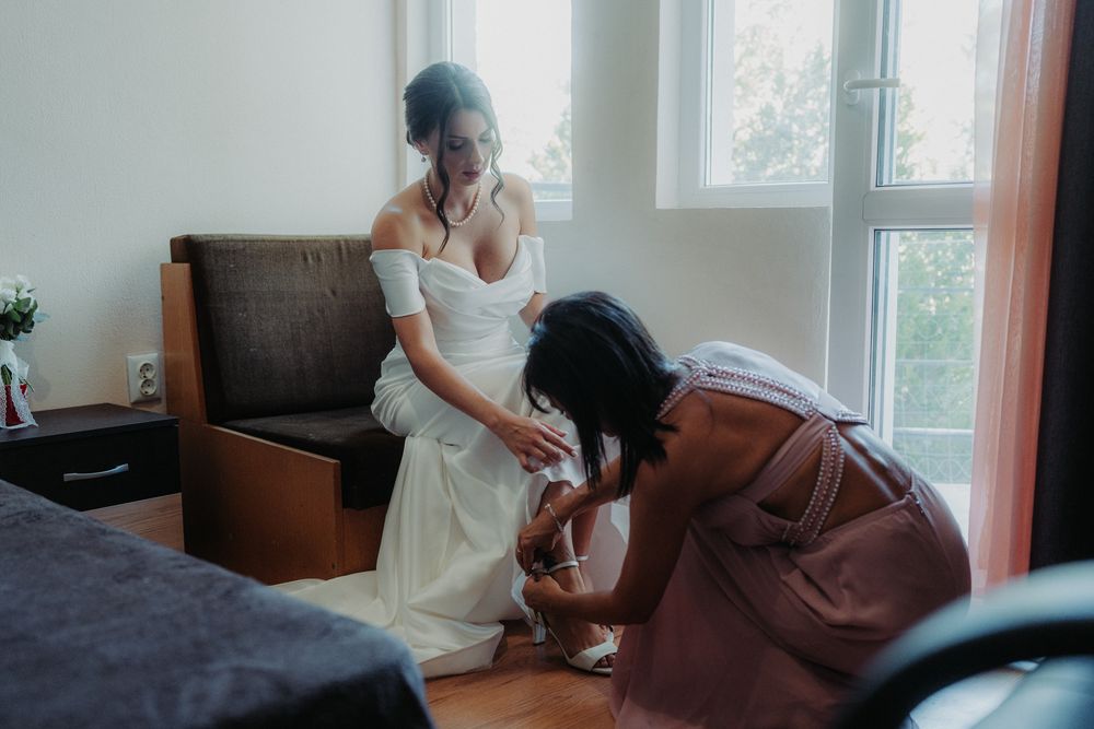 An intimate moment during wedding preparations as final adjustments are made to a white dress.