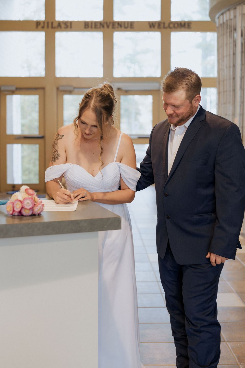 Bride and groom elope at Cape Jourimain Nature Centre, signing of the papers in the welcome centre, rainy October wedding in New Brunswick