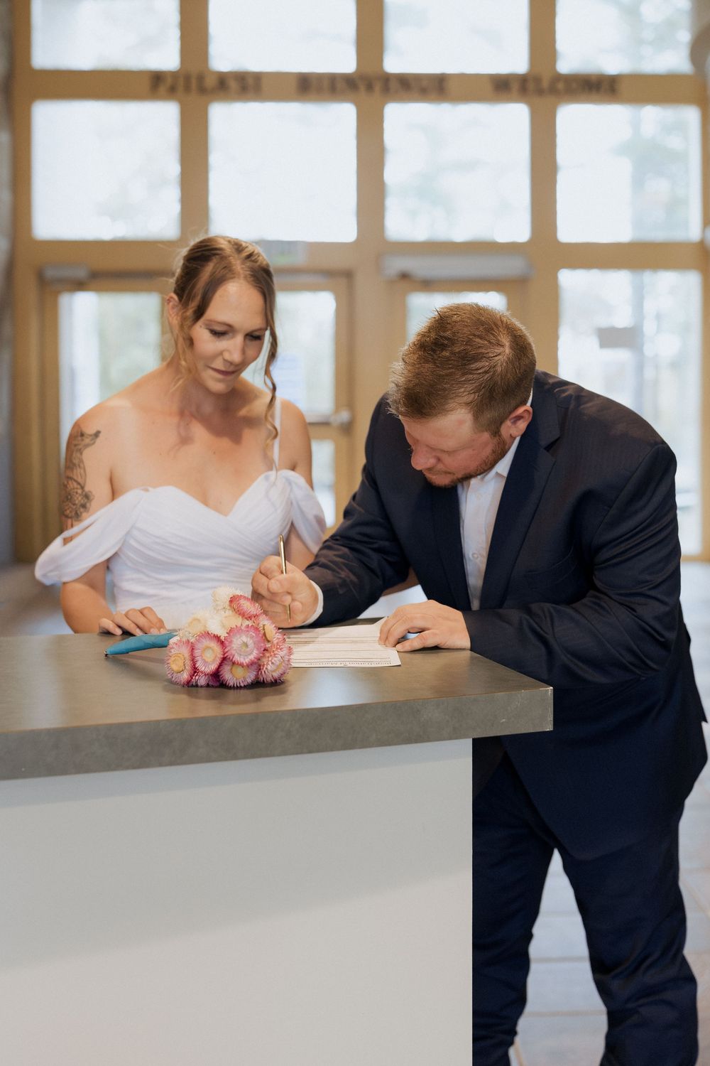 Bride and groom elope at Cape Jourimain Nature Centre, signing of the papers in the welcome centre, rainy October wedding in New Brunswick