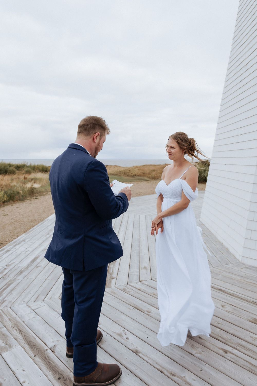Bride and groom exchange vows in front of a lighthouse in New Brunswick, fall October wedding photography Moncton elopement portraits