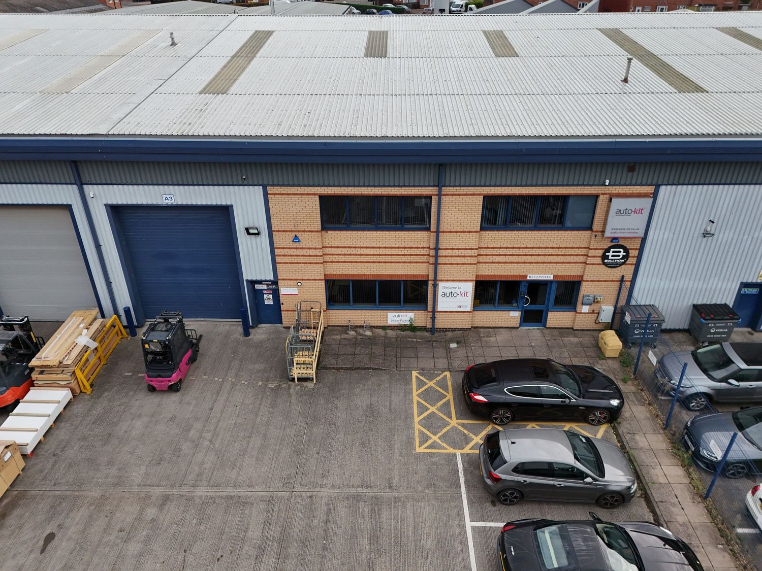 Aerial view of a commercial warehouse facility with loading bays, parked vehicles, and industrial storage units.