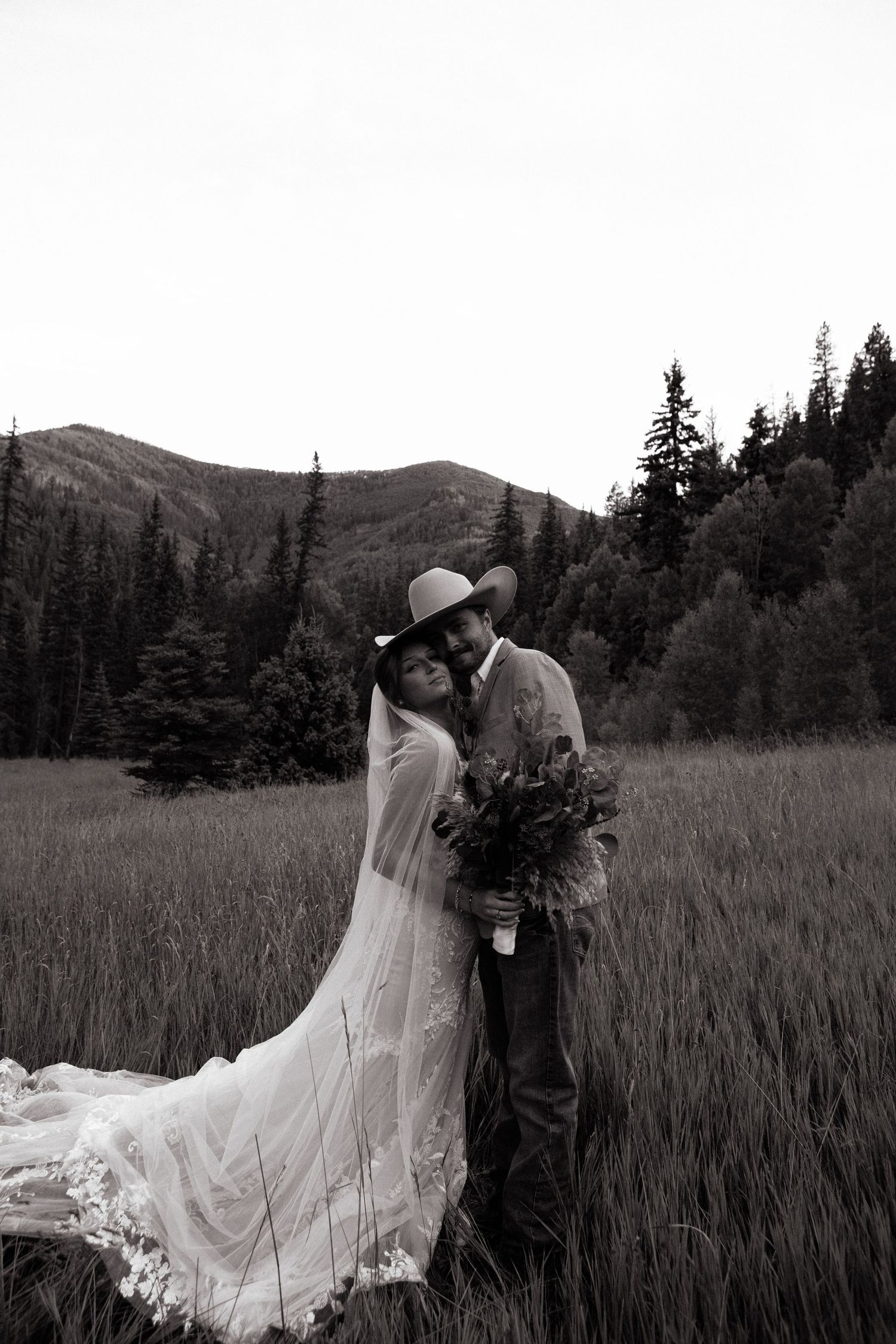 bride and groom squish faces together in the colorado mountains
