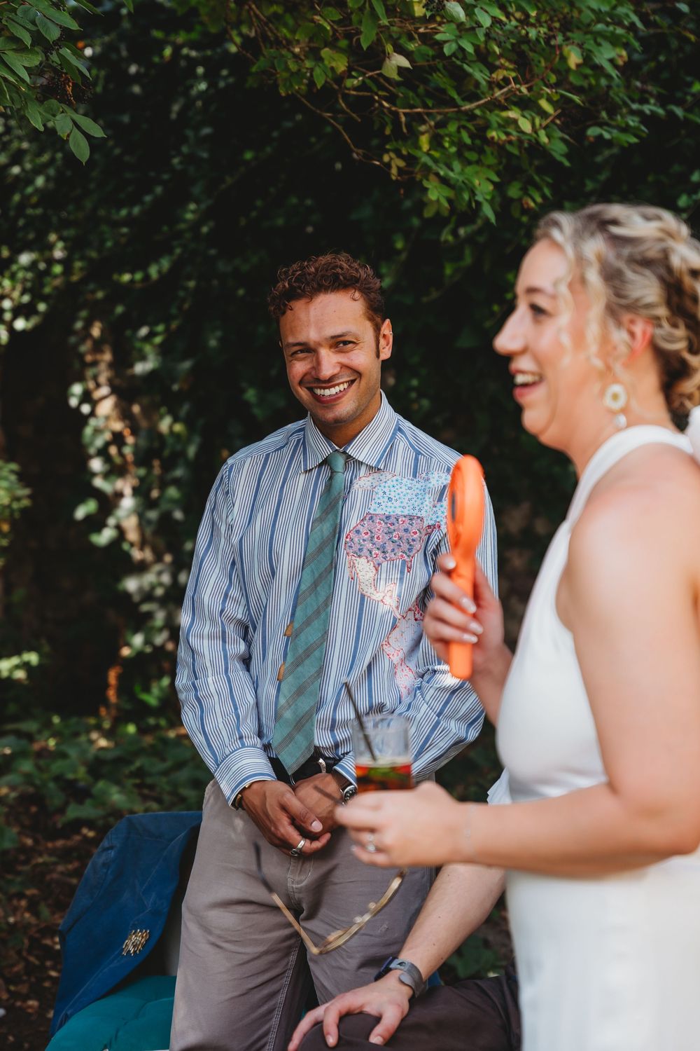 Casual outdoor wedding conversation between guests on a sunny afternoon.