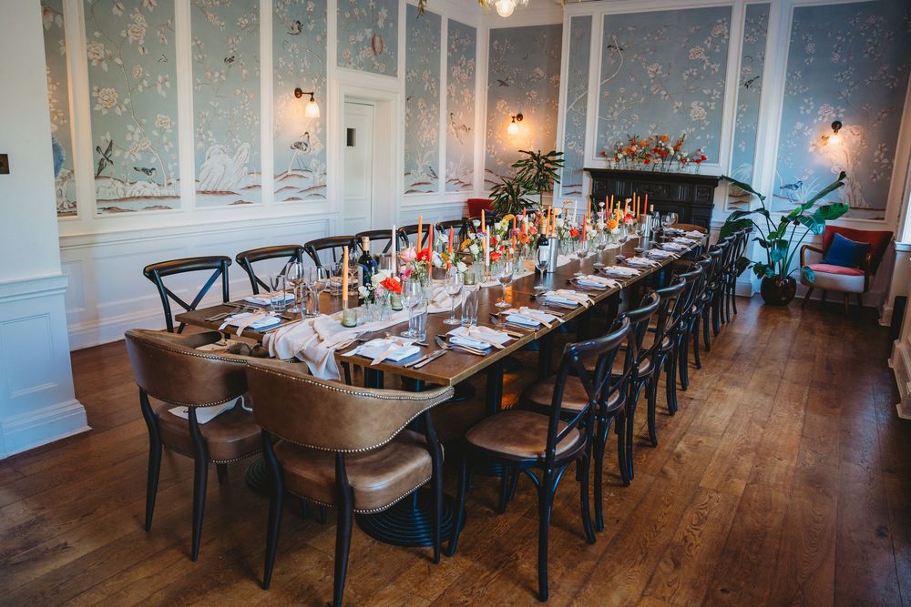 Elegant wedding reception venue with long tables and cross-back chairs in a bright indoor space.
