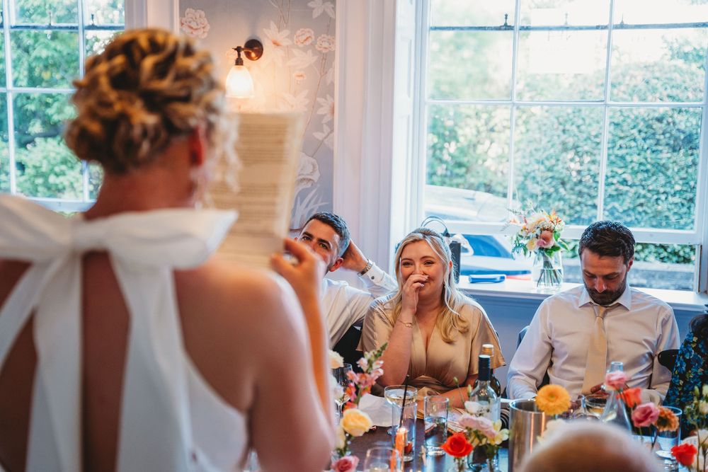 Wedding reception guests sharing emotional moments during speeches and toasts.
