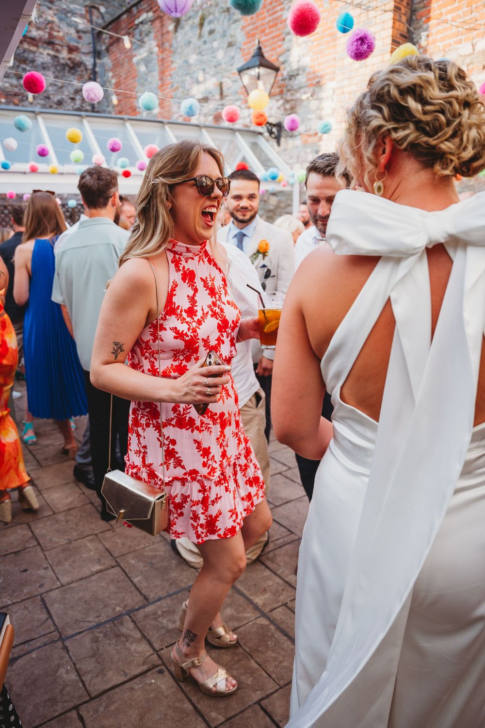 Wedding guests dancing under colorful bunting at outdoor reception.