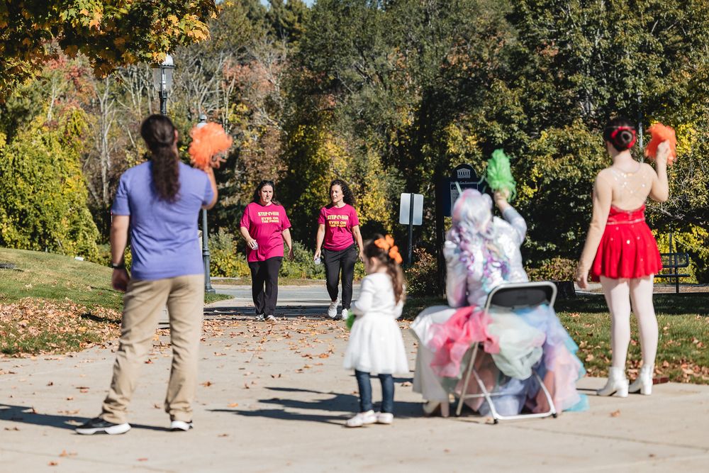 People enjoying a sunny autumn day in the park with colorful balloons and festive attire.