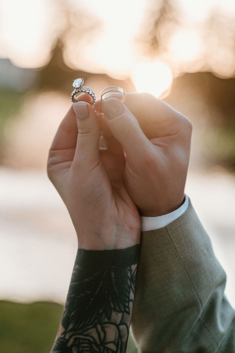 Newlyweds display diamond engagement ring and wedding band together in golden sunset light.
