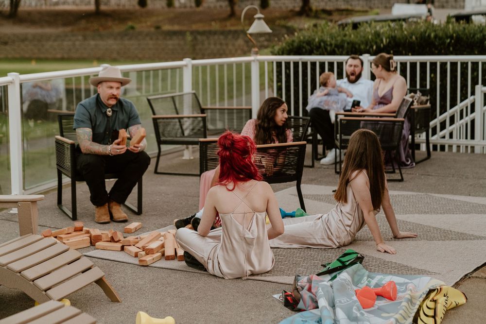 Wedding guests relax and play lawn games on patio during casual outdoor wedding reception.