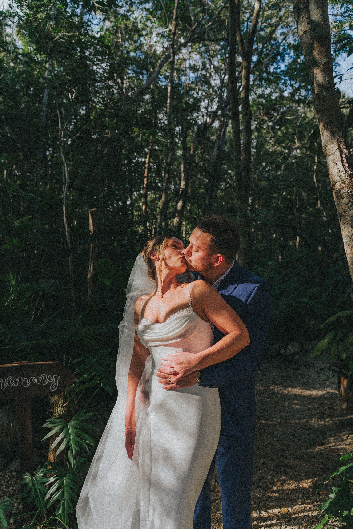 Wedding couple embracing in a brick-walled sunroom with industrial lighting fixtures.