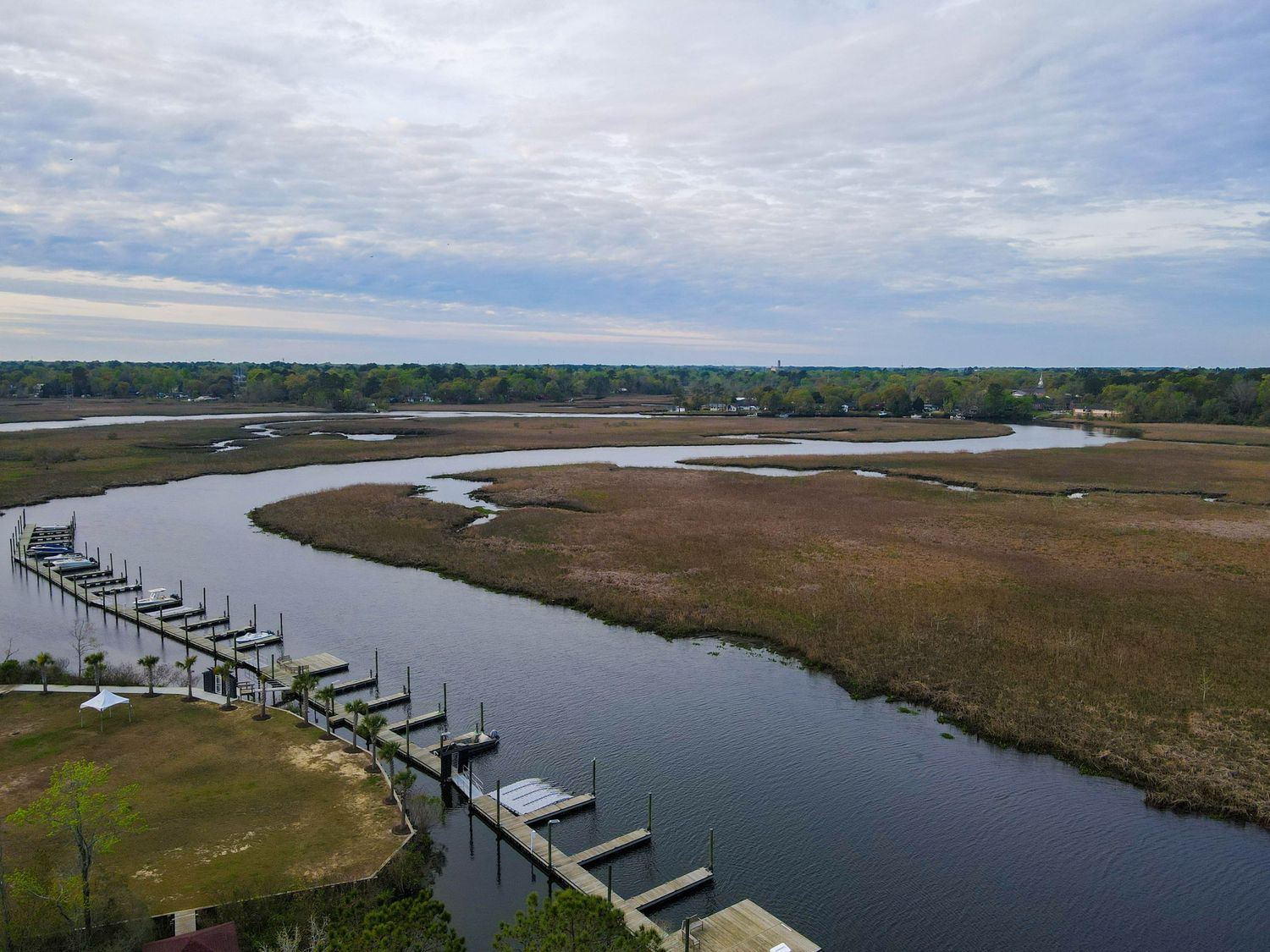 Aerial view of coastal marsh with wooden dock extending into winding river.