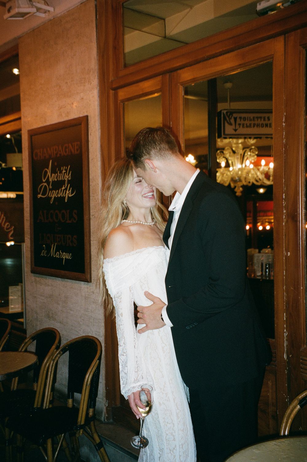 A romantic moment between a couple in formal wedding attire dancing in a dimly lit venue.