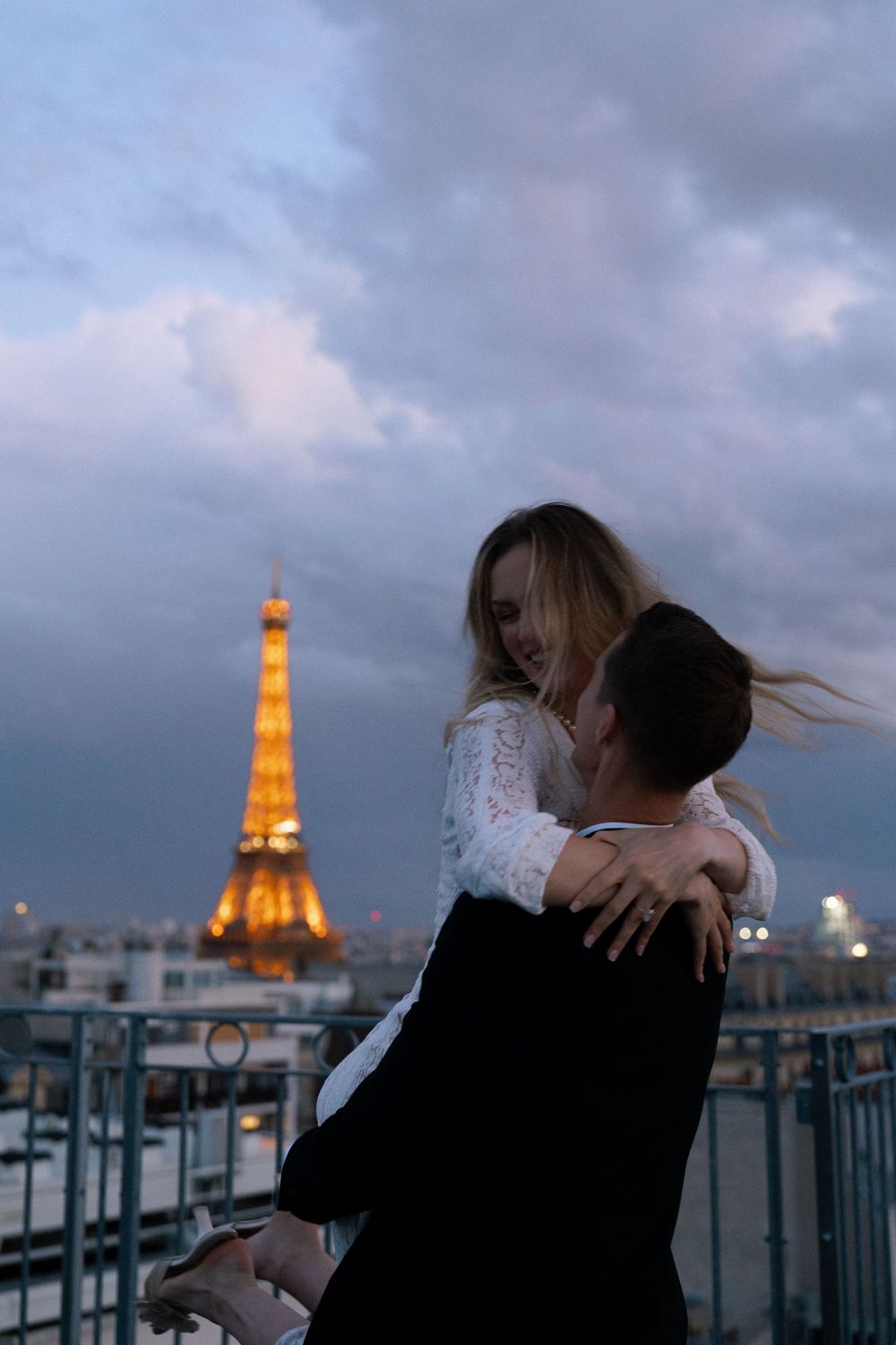 A romantic evening scene in Paris with the illuminated Eiffel Tower glowing against a moody twilight sky. Paris film photographer.