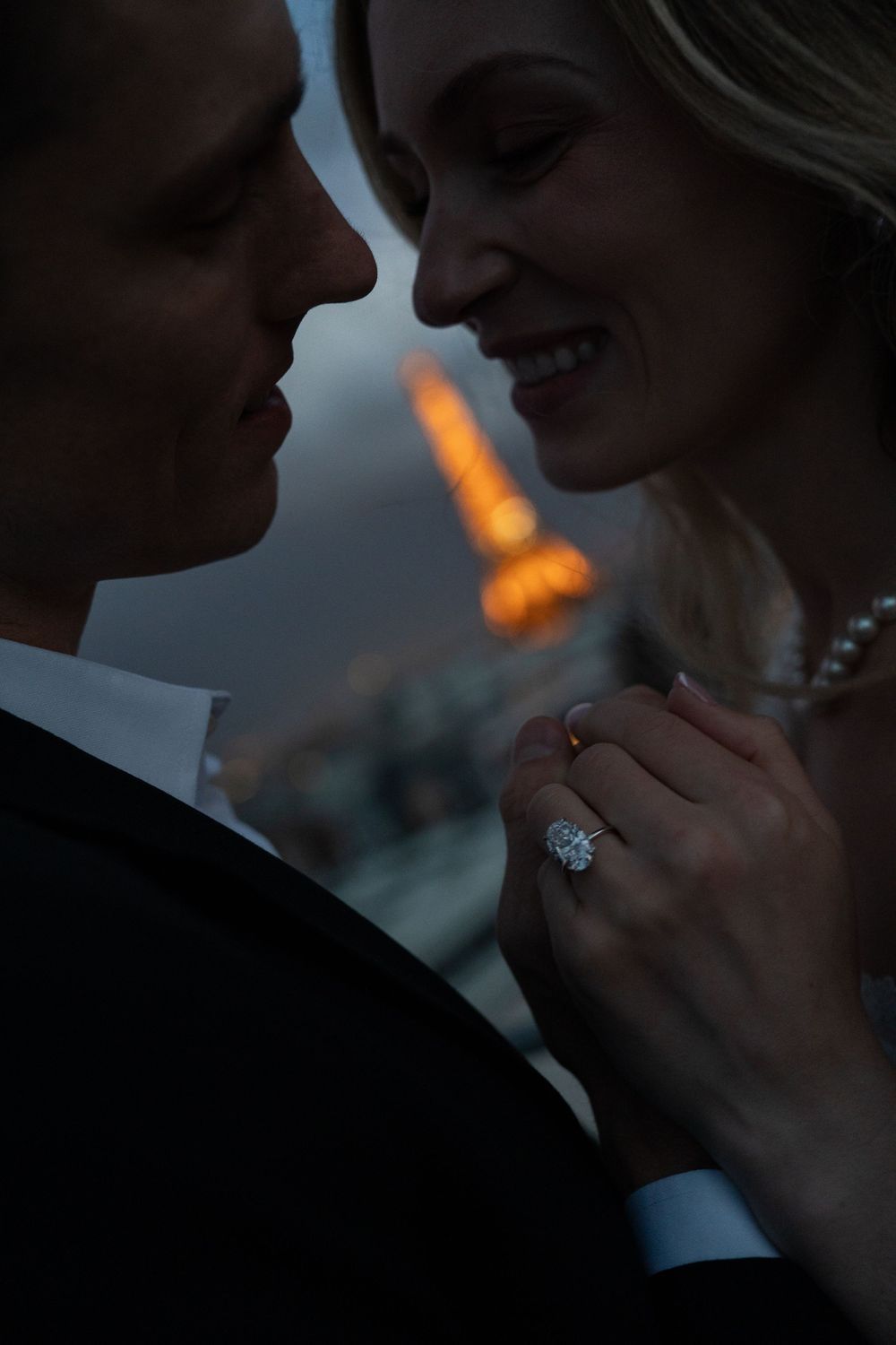 A romantic silhouetted couple shares an intimate moment at dusk with a soft glow in the background.