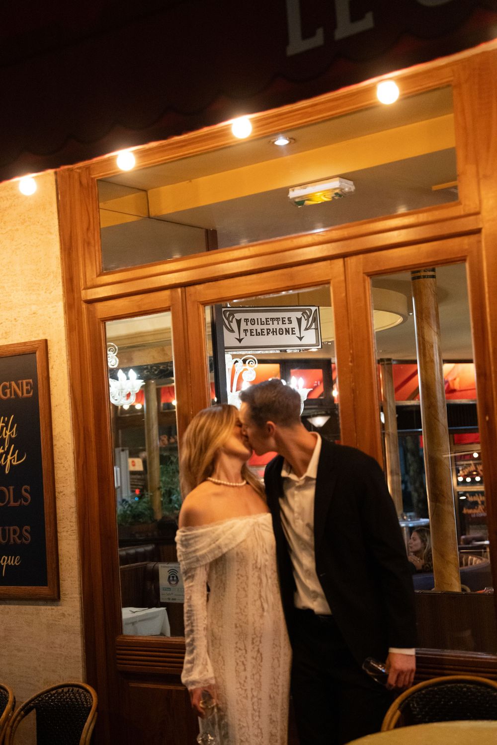 A romantic evening scene outside a French bistro with warm lighting and wooden storefront details.
