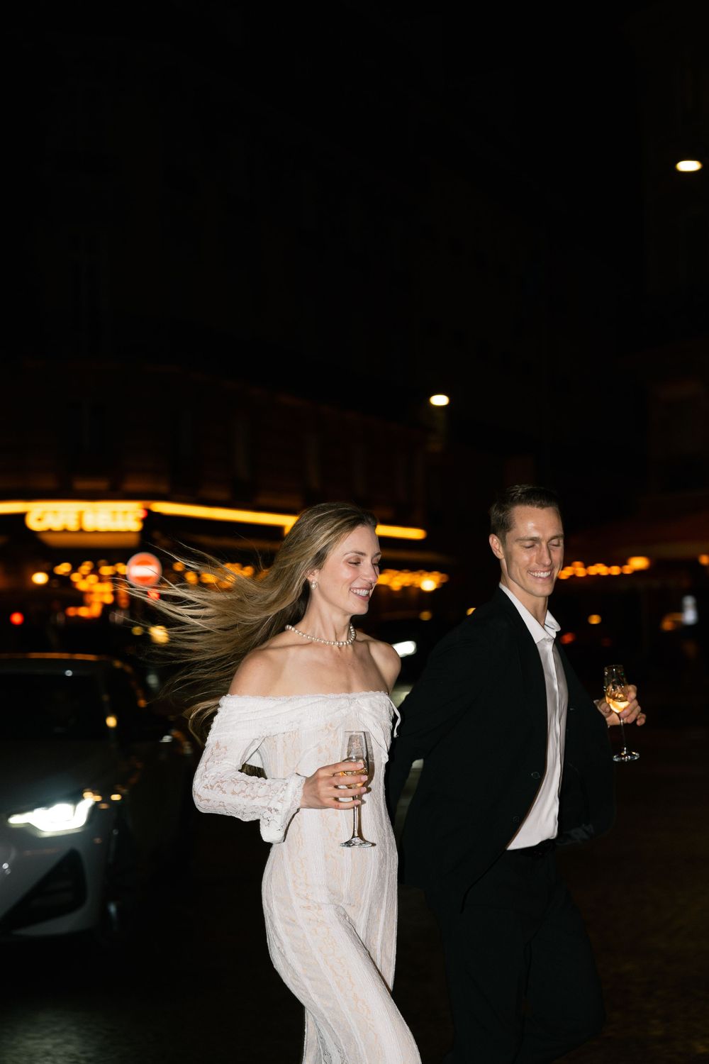 A couple in formal attire dancing together at night, with the bride's white dress flowing in motion.